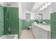 Green-tiled bathroom with combined shower and tub, updated vanity, and excellent lighting at 1232 Corbett Ln, Orlando, FL 32806