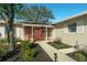Close-up of home's brick front entrance with landscaping and a red front door at 1232 Corbett Ln, Orlando, FL 32806