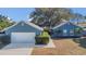 Charming blue home featuring an attached two-car garage, manicured bushes, and a lovely front entrance at 1320 Corte Nueva, Winter Springs, FL 32708