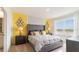 Brightly lit bedroom with yellow accent wall, mirrors, gray headboard, and bedside tables at 1344 Hanoverian Dr, Lake Alfred, FL 33850