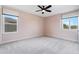 Bedroom with neutral carpet, two windows with views, modern ceiling fan, and light pink walls at 16112 Vetta Dr, Montverde, FL 34756