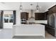 Modern kitchen featuring stainless steel appliances, an island with seating, dark cabinets, and stylish pendant lighting at 16112 Vetta Dr, Montverde, FL 34756