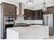Modern kitchen featuring stainless steel appliances, a large island with quartz countertops, dark cabinets, and a pendant lights at 16112 Vetta Dr, Montverde, FL 34756