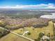 Aerial view showing a sprawling property with trees, a house, and a nearby lake at 1680 Blackwelder Rd, De Leon Springs, FL 32130