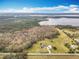 Expansive aerial view of a large lot home with a backdrop of lush trees and a lake at 1680 Blackwelder Rd, De Leon Springs, FL 32130