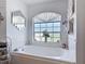 Soaking tub under a large window with decorative accents, a mirrored clock, and neutral tile at 1680 Blackwelder Rd, De Leon Springs, FL 32130