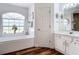 Elegant bathroom featuring a soaking tub under a large window, stylish fixtures, and wood flooring at 1680 Blackwelder Rd, De Leon Springs, FL 32130