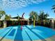 Community splash pad with colorful water features on a bright blue surface, surrounded by lush greenery and black fencing at 2600 Avian Loop, Kissimmee, FL 34741