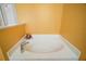 Clean white bathtub in a corner setting with bright yellow walls and a window at 2655 Sheila Dr, Apopka, FL 32712