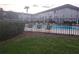 Community pool is fenced and surrounded by shrubbery, lounge chairs, and umbrellas at 333 Lake Howard Nw Dr # 201C, Winter Haven, FL 33880