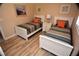 Bright bedroom showcasing two twin beds with striped bedding and orange pillows, complemented by neutral walls and wood floors at 4153 S Atlantic Ave # 1070, New Smyrna Beach, FL 32169