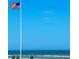 American flag waving over the ocean under a bright blue sky, symbolizing pride and patriotism, near community amenities at 4153 S Atlantic Ave # 1070, New Smyrna Beach, FL 32169