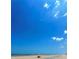 Distant ocean view of the coast with beachgoers relaxing under a colorful umbrella against a backdrop of blue sky and white clouds at 4153 S Atlantic Ave # 1070, New Smyrna Beach, FL 32169