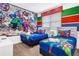 Themed bedroom with two twin beds with blue Marvel bedding, a decorative mural, and colorful striped accent walls at 4164 Paragraph Dr, Kissimmee, FL 34746