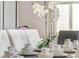 Close-up of elegantly set dining table with white orchid centerpiece and dishware at 4164 Paragraph Dr, Kissimmee, FL 34746