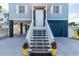 Inviting entryway featuring white stairs, a dark blue garage door and colorful planters at 435 Jessamine Ave, New Smyrna Beach, FL 32169