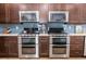 Modern kitchen featuring double ovens, stainless steel appliances, dark wood cabinetry, and a stylish blue backsplash at 435 Jessamine Ave, New Smyrna Beach, FL 32169