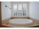 Luxurious soaking tub with tile surround, a golden faucet, and plantation shutters at 450 Lakewood Dr, Winter Park, FL 32789