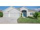 Beautiful one-story home featuring a well-manicured lawn, two-car garage, and a charming light-blue front door at 6148 Gracie Pl, Lakeland, FL 33812