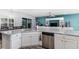 Modern kitchen with stainless steel appliances, white cabinetry, and stone countertops opens to the living room at 6148 Gracie Pl, Lakeland, FL 33812