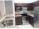 Kitchen showcasing stainless steel appliances, granite countertops, and dark wood cabinetry at 6412 Queens Borough Ave # 109, Orlando, FL 32835