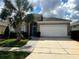 Charming one-story home with a well-manicured lawn, palm tree, and a two-car garage at 8157 Fan Palm Way, Kissimmee, FL 34747