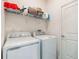 Well-equipped laundry room with a side-by-side washer and dryer and storage shelving at 954 Laurel View Way, Groveland, FL 34736