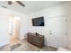 Open living area with tile floors, ceiling fan, a TV, and a view of a hallway with a bedroom and bathroom at 954 Laurel View Way, Groveland, FL 34736