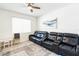 Bright living room featuring plush black leather seating and a ceiling fan for added comfort at 954 Laurel View Way, Groveland, FL 34736