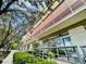 Modern building entrance with glass doors, greenery, and metal accents, set against a sunny sky with tree branches at 101 S Eola Dr # 1208, Orlando, FL 32801