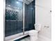 Modern bathroom with a sleek glass-enclosed shower featuring unique blue tiles and a new toilet at 1039 Morningside Dr, Eustis, FL 32726