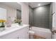 Modern bathroom features a tub with gray tiled walls, a white vanity and fresh flowers at 1045 Morningside Dr, Eustis, FL 32726