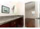 Bathroom with wood cabinets, granite counters, and access to the bedroom at 1090 Parnell Ct, Deltona, FL 32738