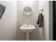 Well-lit half bath featuring a pedestal sink, decorative mirror, and modern fixtures at 1262 Stonewater Cir, Ocoee, FL 34761
