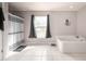 Bathroom featuring a soaking tub, large window with dark curtains and light tile flooring at 1262 Stonewater Cir, Ocoee, FL 34761