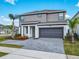 Charming two-story gray home with a two-car garage, palm trees, and a paved driveway on a sunny day at 178 Marcello Blvd, Kissimmee, FL 34746