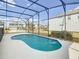 A kidney-shaped pool is surrounded by a screened enclosure and white concrete with neighborhood homes visible beyond at 178 Marcello Blvd, Kissimmee, FL 34746