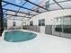 A kidney-shaped pool is surrounded by a screened enclosure and white concrete with an adjacent white house at 178 Marcello Blvd, Kissimmee, FL 34746