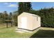 Exterior view of new storage shed in backyard surrounded by green grass, hedges, and trees at 2006 Deborah Dr, Orlando, FL 32817