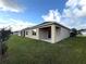 An exterior shot of the backyard features a covered patio, a lush green lawn, and neutral colored walls at 2877 Sunridge Loop, St Cloud, FL 34771