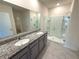 Modern bathroom featuring double sinks, granite countertops, and a glass-enclosed shower at 2877 Sunridge Loop, St Cloud, FL 34771