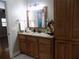 Well-lit bathroom featuring granite countertops, wood cabinets and large mirror at 2929 Lakeshore Dr, Mount Dora, FL 32757