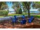 Inviting outdoor space with blue Adirondack chairs around a fire pit overlooking the water at 2929 Lakeshore Dr, Mount Dora, FL 32757