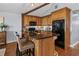 Kitchen with wood cabinets, granite counters, island with seating, black appliances, and hardwood floors at 2929 Lakeshore Dr, Mount Dora, FL 32757