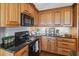 Cozy kitchen featuring wood cabinets, granite countertops, and black appliances including a modern range at 2929 Lakeshore Dr, Mount Dora, FL 32757