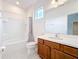 Bright bathroom featuring a shower-tub combo, wooden vanity with white countertop, and a light gray tile floor at 299 Marcello Blvd, Kissimmee, FL 34746