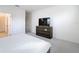 Bedroom with a television on a dresser, neutral carpeting, and an adjacent bathroom and closet at 299 Marcello Blvd, Kissimmee, FL 34746