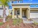 Inviting entrance featuring a covered porch with stone pavers, a white front door, and meticulously landscaped garden beds at 299 Marcello Blvd, Kissimmee, FL 34746