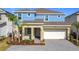 Two-story home featuring a two-car garage, a combination of blue and beige paint, and a well-maintained front yard at 299 Marcello Blvd, Kissimmee, FL 34746