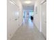Bright hallway with tile flooring, white walls, and doors, leading to a view of the living area and staircase at 299 Marcello Blvd, Kissimmee, FL 34746